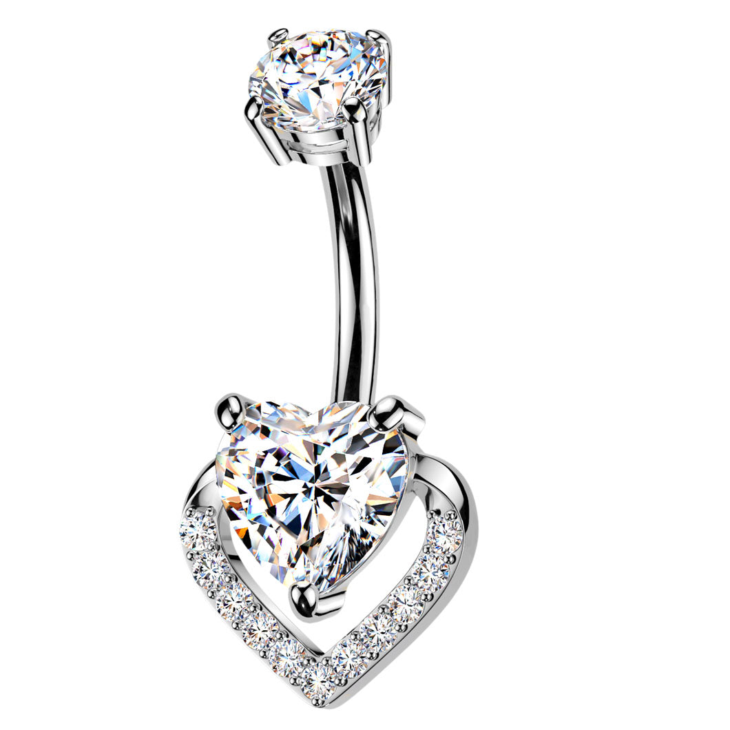 A silver-toned belly button ring featuring a curved barbell with a large heart-shaped clear gemstone at the bottom and a smaller round clear gemstone at the top, set against a plain white background.
