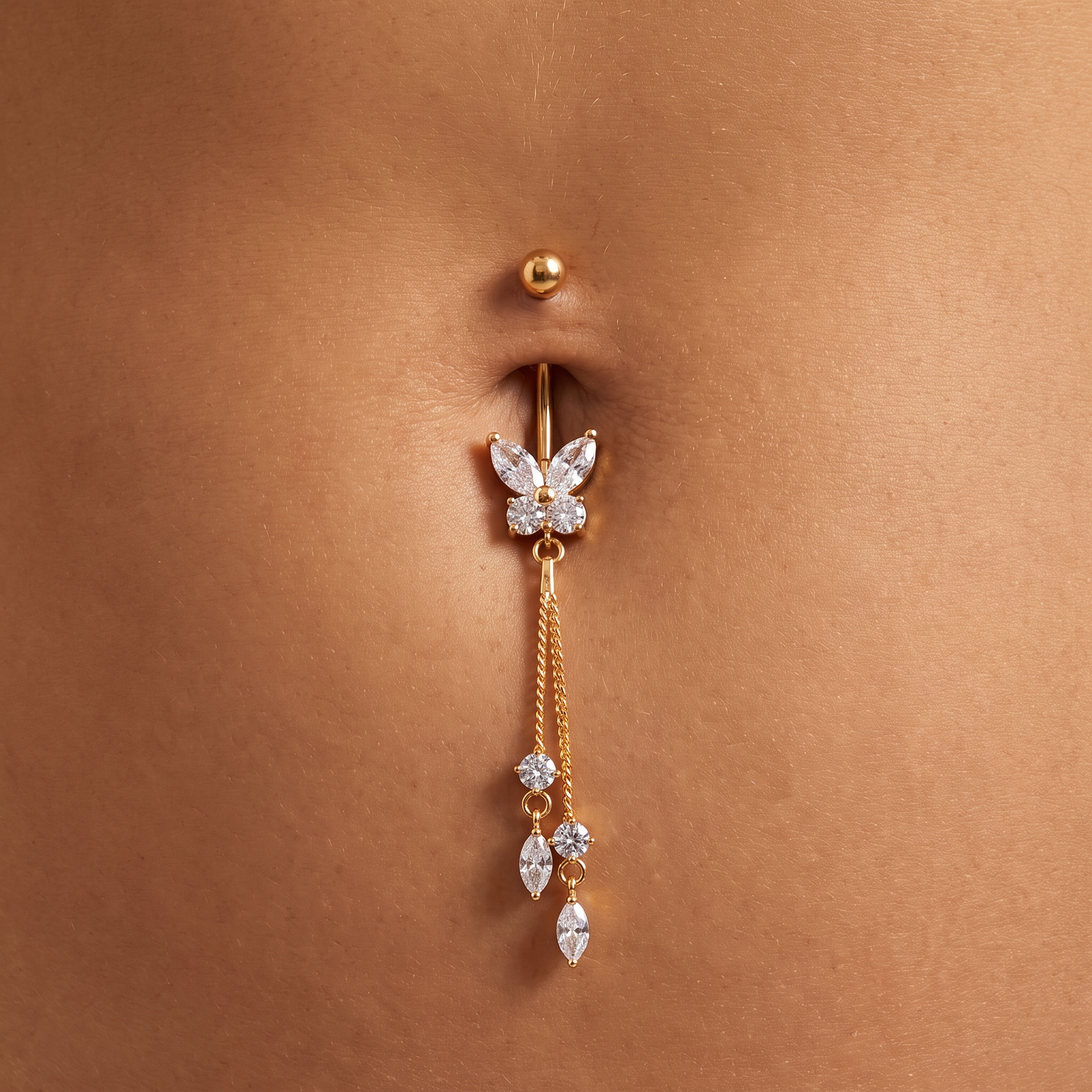 A gold-plated belly button ring with a butterfly charm set with clear rhinestones and dangling crystal accents, shown worn on a person's navel.