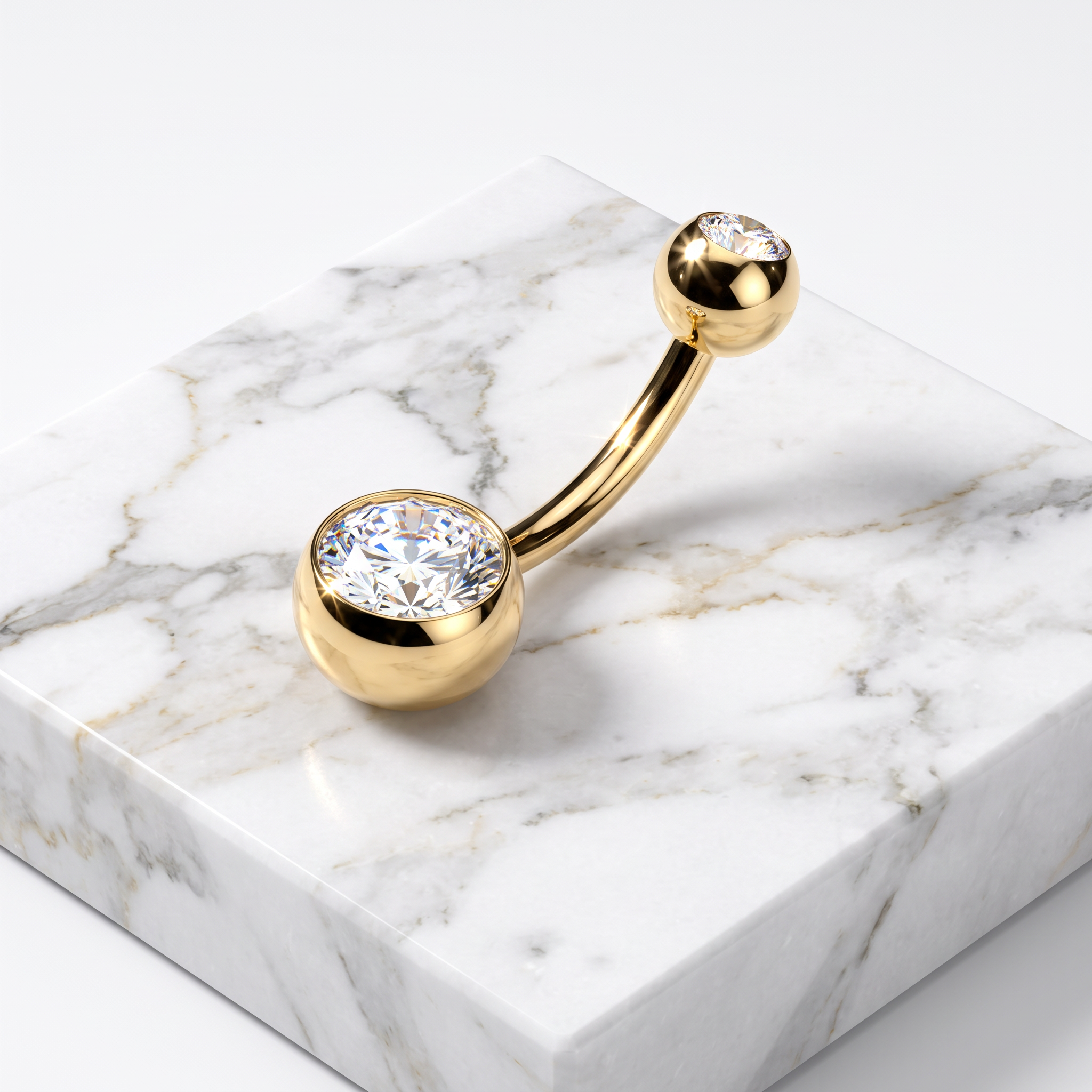 Gold curved barbell navel piercing with two round bezel-set clear cubic zirconia stones, displayed on a white and gray marble block.