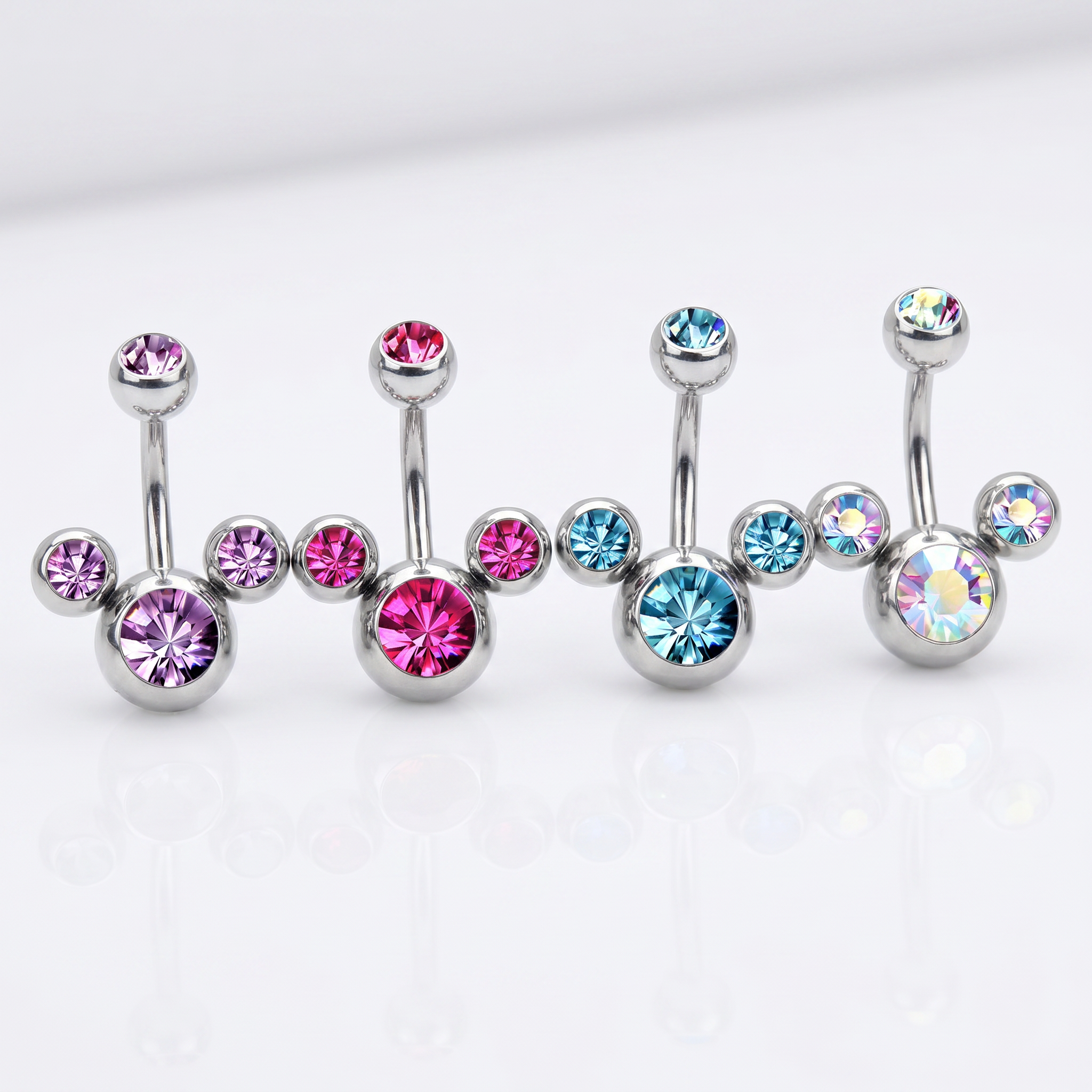 Four silver-toned navel barbell piercings with round faceted gemstones in pink, light blue, and iridescent colors, arranged on a clean white background.