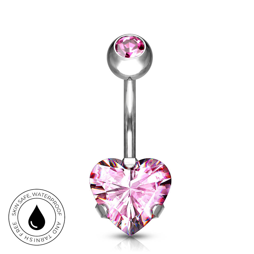 A silver-toned navel barbell piercing with a faceted pink heart-shaped crystal and a smaller pink crystal at the top of the curved bar, shown on a white background with a circular 'Skin Safe Waterproof' badge in the lower left.
