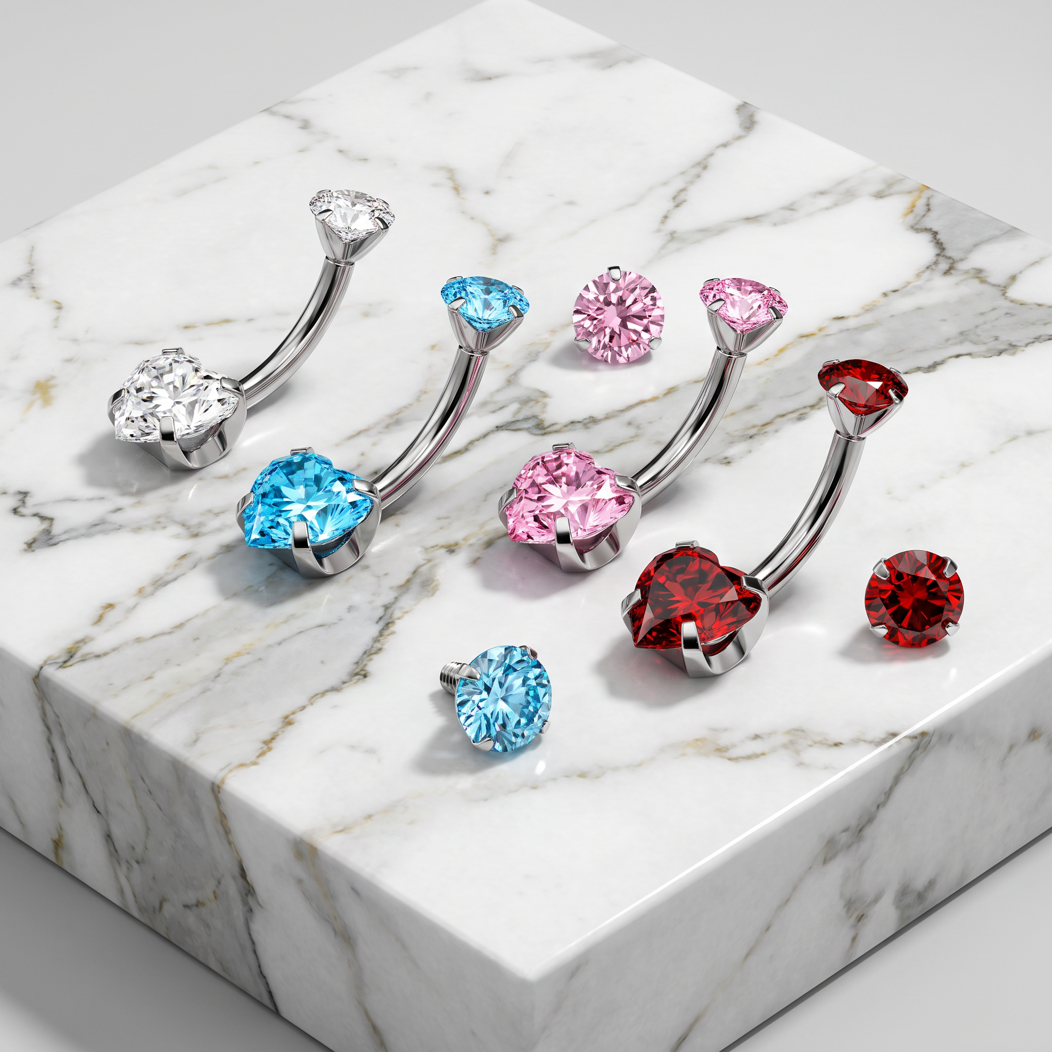 Three curved barbell belly button piercings with heart-shaped crystal studs in silver, blue, pink, red, and clear, arranged on a white marble block.
