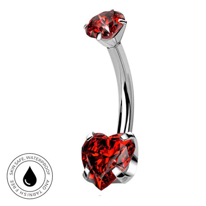 A curved barbell belly button ring with a top round red gemstone and a bottom heart-shaped red gemstone in a polished silver-tone setting, shown on a white background with a circular skin-safe waterproof badge in the lower left.