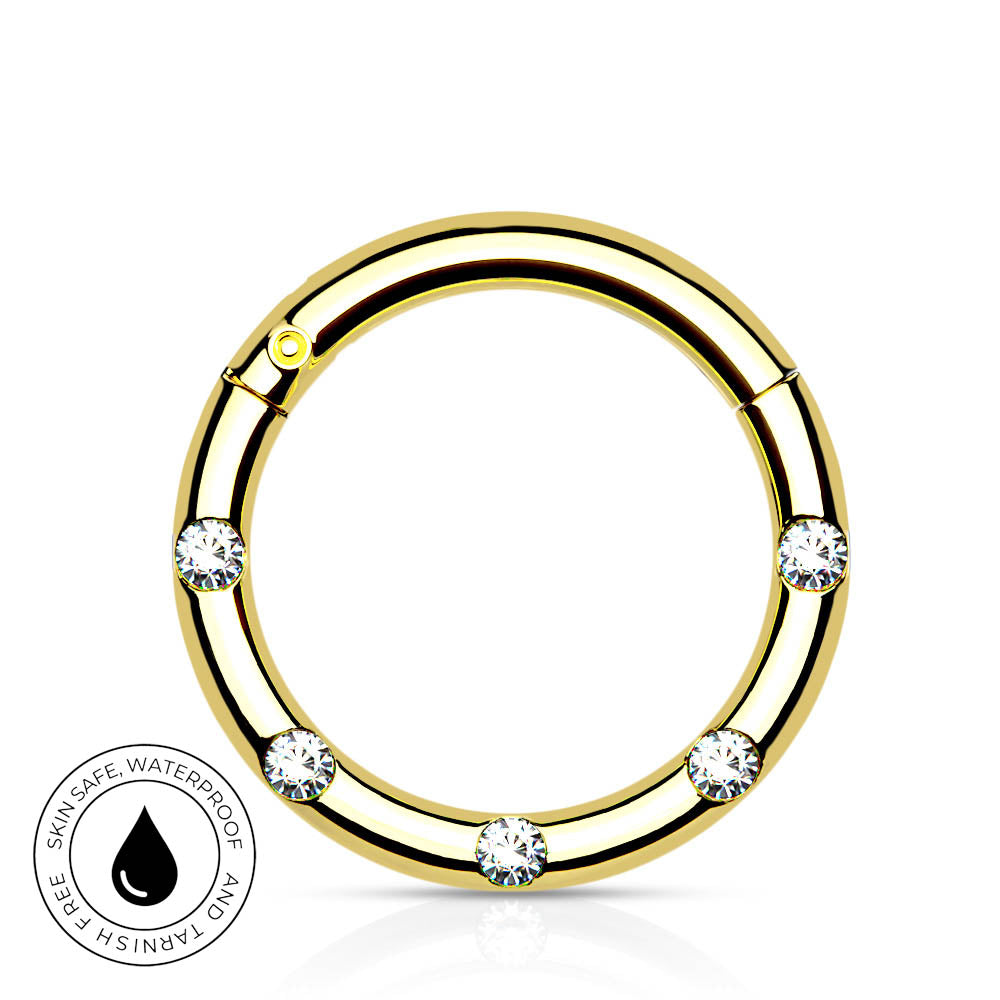 A gold-plated circular ring with five clear, round-cut gemstones spaced evenly around the band, shown on a white background with a small circular 'Skin Safe Waterproof' badge in the lower-left corner.