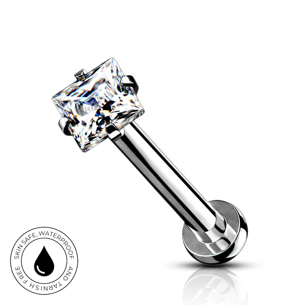 A silver-toned labret piercing barbell with a clear princess-cut cubic zirconia gemstone in a four-prong setting, shown on a white background with a small circular 'Skin Safe Waterproof' badge in the lower-left corner.