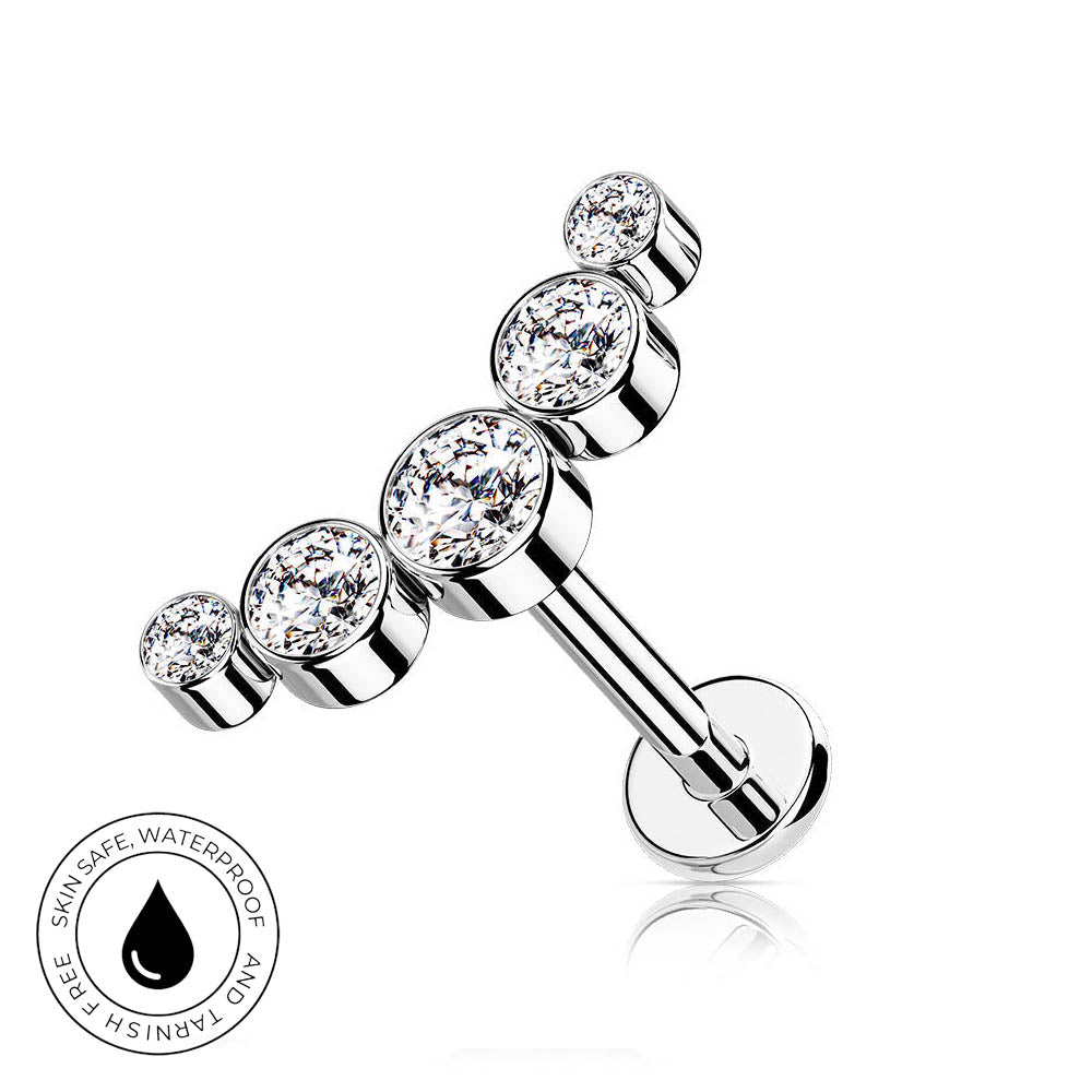 A silver-toned barbell-style body jewelry piece with four clear round gemstones, shown on a white background with a small circular skin-safe waterproof badge in the lower left.