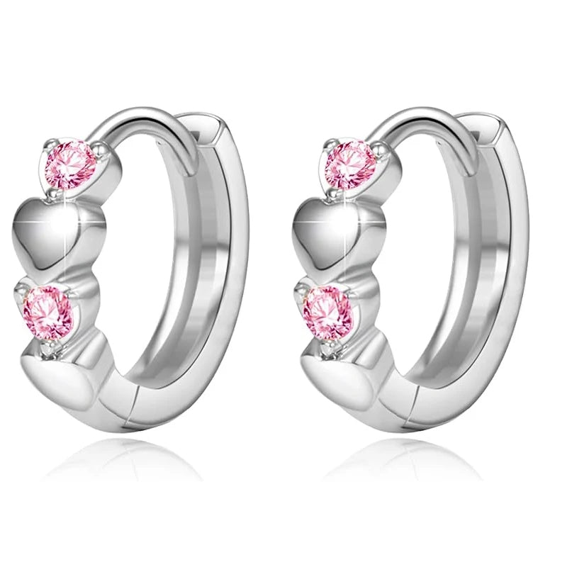 A pair of silver huggie hoop earrings decorated with three stacked heart charms, each accented with a round pink gemstone, shown on a clean white background with a soft reflection.