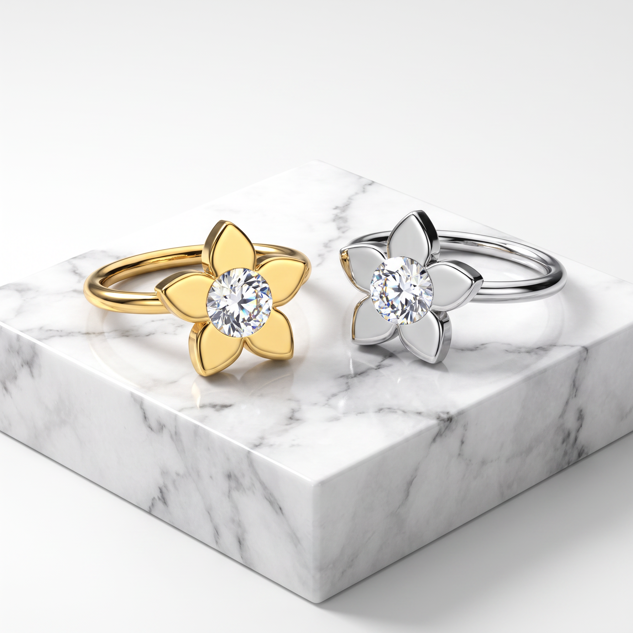 Two flower-shaped rings displayed on a white marble block against a clean white background. One ring is gold with a clear round center stone, and the other is silver with a matching clear round center stone.