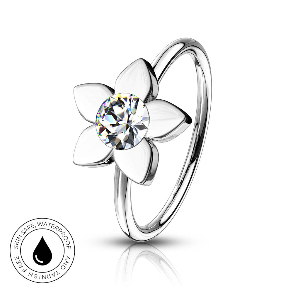 A silver-toned flower-shaped ring with a clear round-cut center stone, shown on a white background with a small circular 'skin-safe waterproof' badge in the lower left corner.