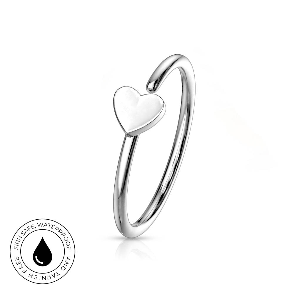 A polished silver-toned ring with a small heart-shaped charm, shown on a clean white background with a circular 'Skin Safe Waterproof' badge in the lower-left corner.