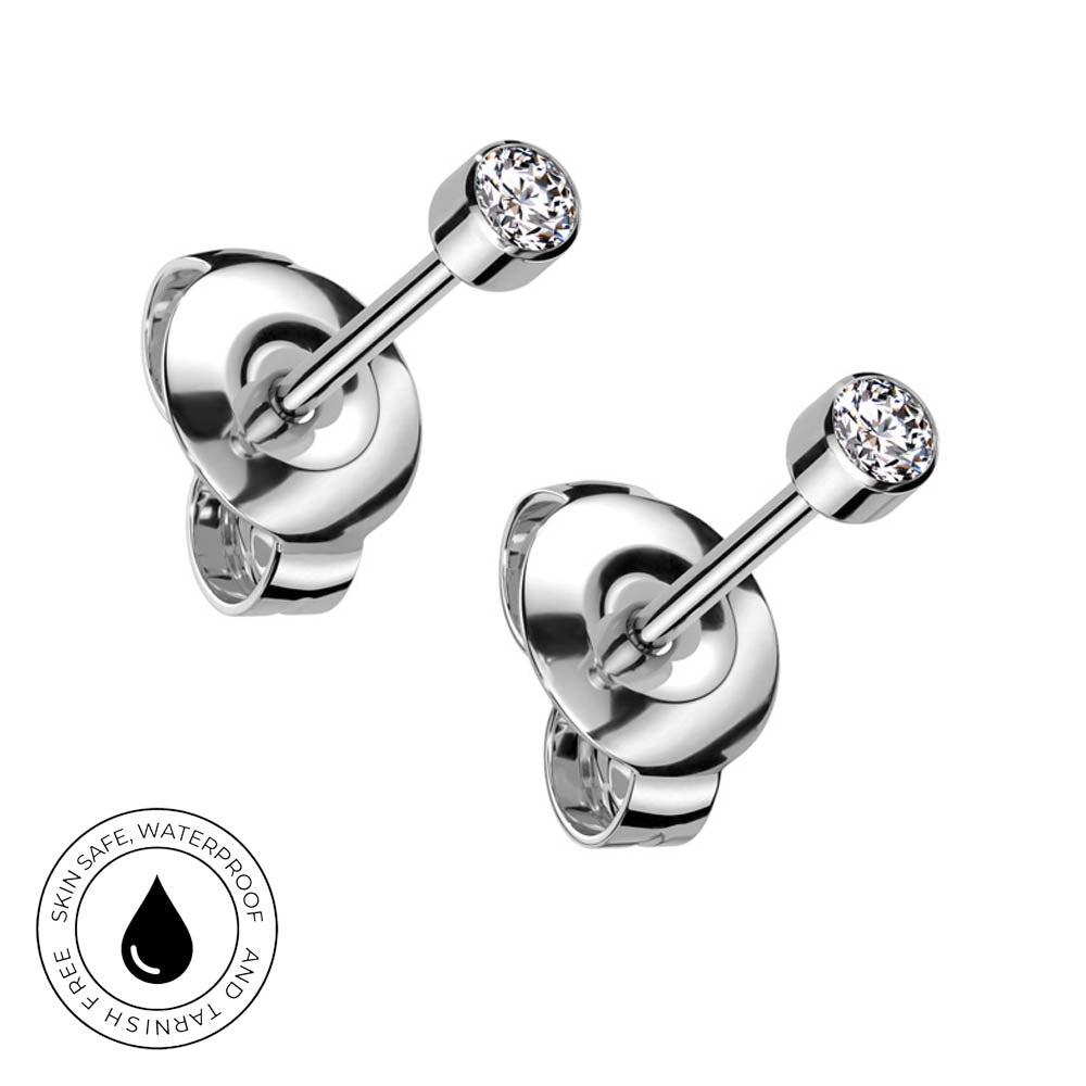 Two silver-toned labret stud earrings with round bezel-set clear gemstones, shown on a white background with a circular 'Skin Safe Waterproof' badge in the lower left corner.