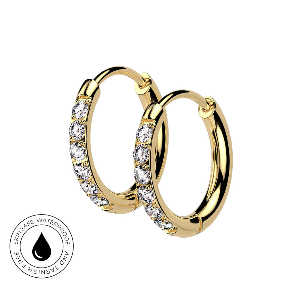 A pair of gold hoop earrings with clear pavé-set stones on a white background, featuring a circular 'Skin Safe Waterproof' badge in the bottom-left corner.