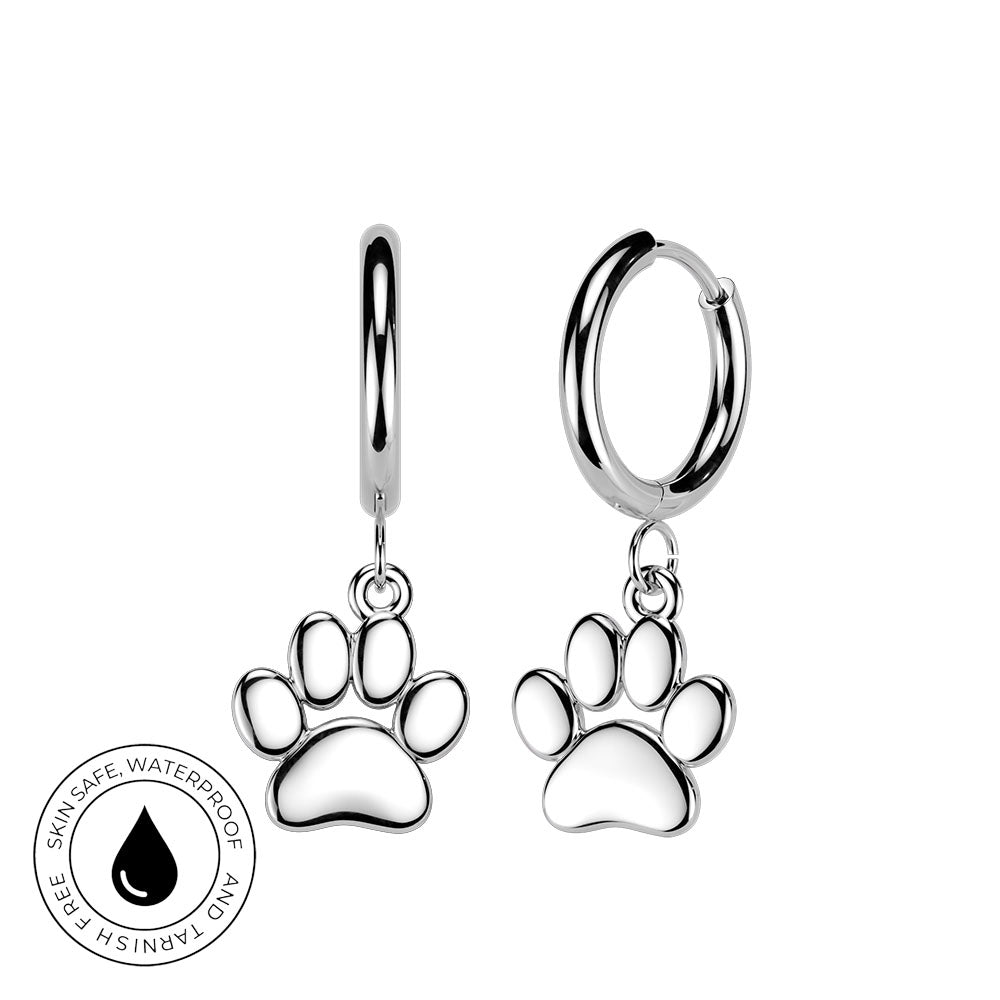 A pair of silver huggie hoop earrings with dangling paw print charms, shown on a plain white background with a circular 'Skin Safe Waterproof' certification badge in the lower-left corner.