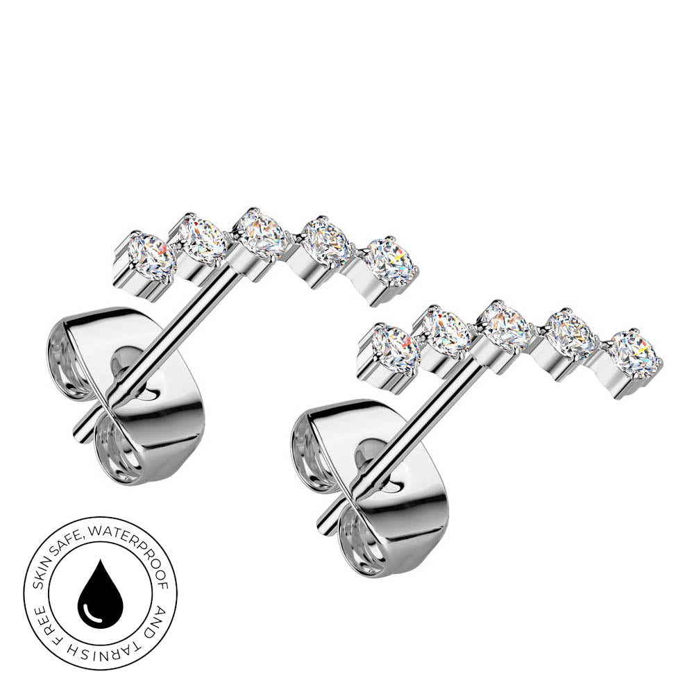 A pair of silver-toned stud earrings with five clear round-cut gemstones on each earring, shown on a white background with a circular 'Skin Safe Waterproof' badge in the lower left corner.