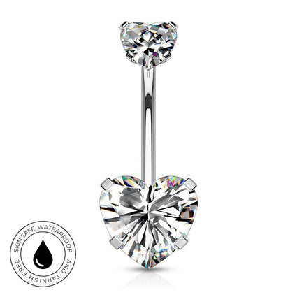 A silver-toned belly button ring with a heart-shaped clear gemstone at the bottom and a smaller heart-shaped gemstone at the top, shown on a white background with a circular skin-safe waterproof badge in the lower left.