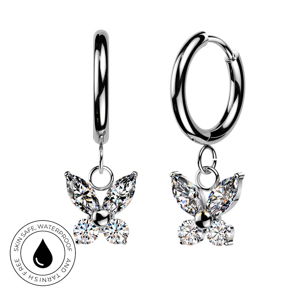 A pair of silver hoop earrings with dangling butterfly charms set with clear sparkling stones, shown on a white background with a circular skin-safe waterproof badge in the lower left.