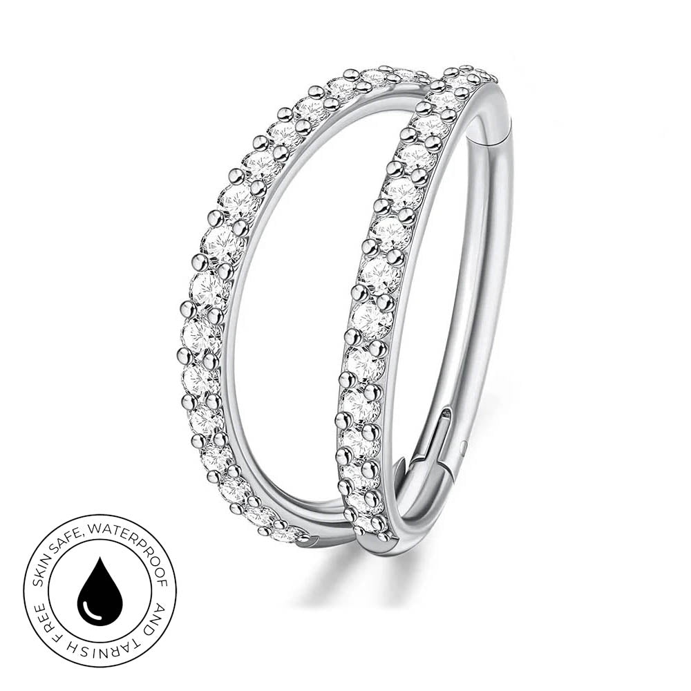A silver-toned double-band ring with clear pavé stones on a white background, featuring a circular inset badge that reads 'SKIN SAFE WATERPROOF' and 'TARNISH FREE'.