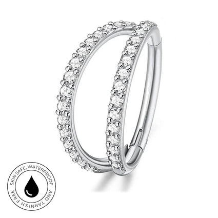 A silver-toned double-band ring with clear pavé stones on a white background, featuring a circular inset badge that reads 'SKIN SAFE WATERPROOF' and 'TARNISH FREE'.