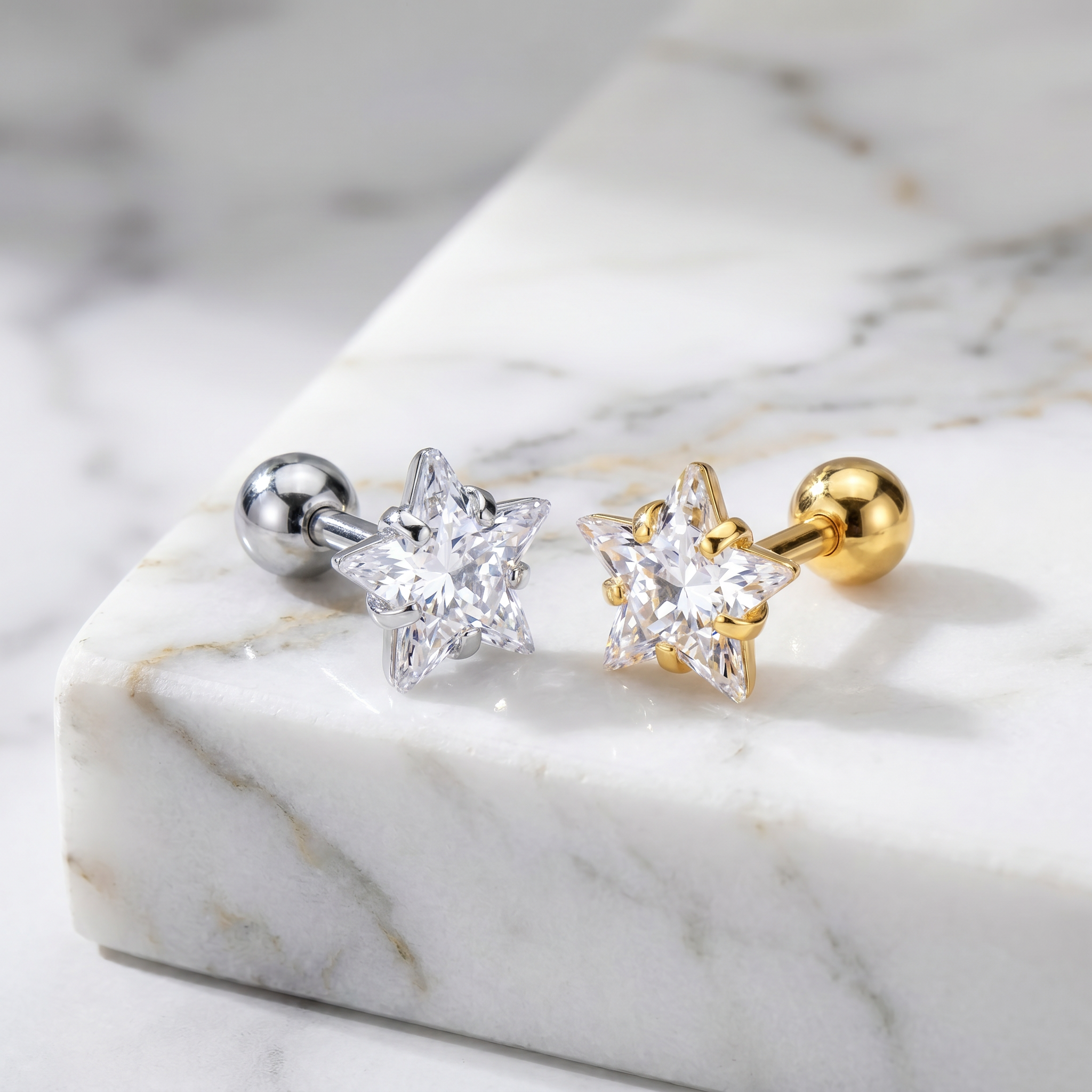 Two star-shaped stud earrings displayed on a white marble slab. One earring has a silver-toned metal setting and ball back, and the other has a gold-toned metal setting and ball back.