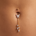 A gold-plated belly button ring with a butterfly charm set with clear rhinestones and dangling crystal accents, shown worn on a person's navel.
