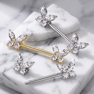 Sterling silver and yellow gold butterfly body jewelry with clear marquise-cut crystals, arranged on a white marble background.