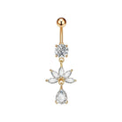 A gold-plated belly button ring featuring a round ball at the top, a clear round gemstone, a flower-shaped cluster of clear gemstones, and a teardrop-shaped clear gemstone dangling at the bottom, shown on a plain white background.