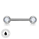 A silver-toned labret piercing barbell with two round bezel-set clear gemstones, shown on a white background with a circular 'skin-safe waterproof' badge in the lower-left corner.