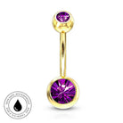 Gold-plated curved barbell navel jewelry with a faceted purple gemstone on each end, shown on a white background with a circular 'Skin Safe Waterproof' badge in the bottom-left corner.
