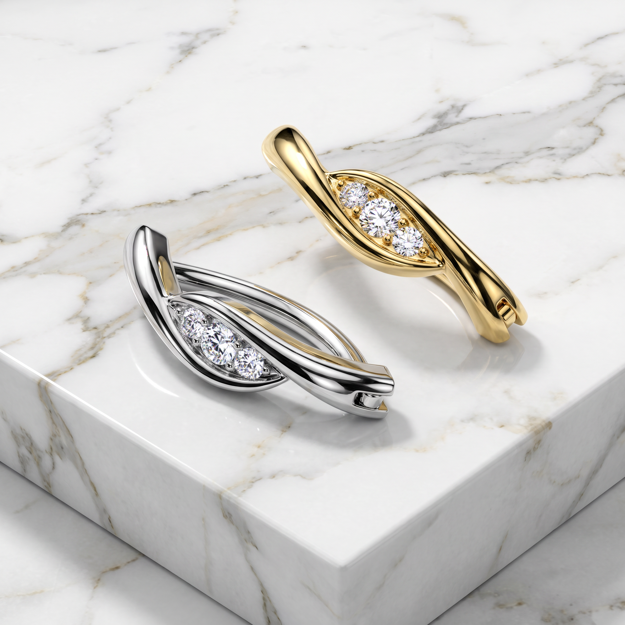 Two twisted leaf-shaped earrings with pavé-set clear stones, shown on a white marble block. One earring is yellow gold and the other is silver, photographed in a clean studio setting.