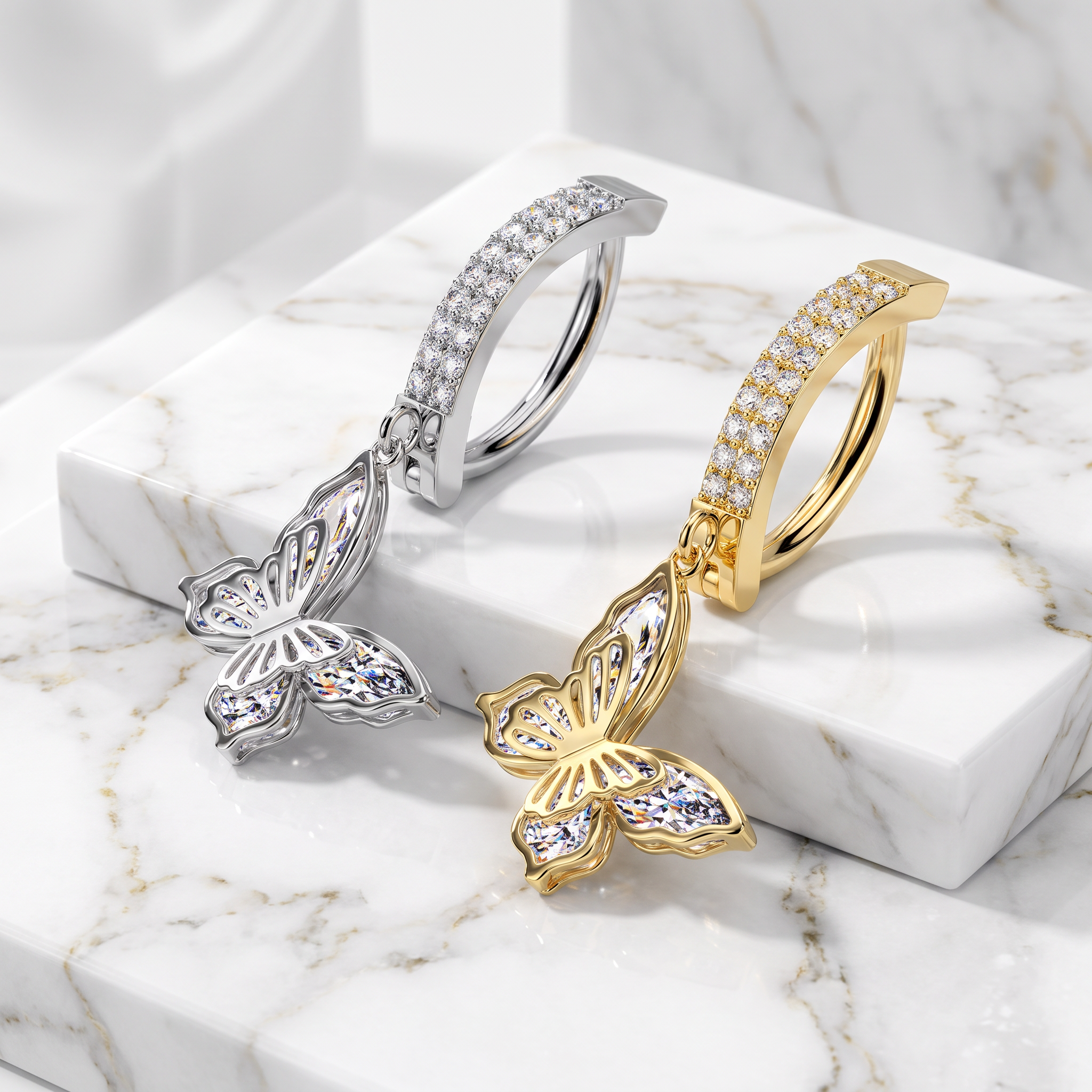 Two butterfly-shaped hoop earrings displayed on a white marble block. One earring is silver-toned with clear stones, and the other is gold-toned with clear stones.