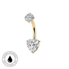 Gold curved barbell navel piercing with a heart-shaped clear gemstone and a round clear gemstone, shown on a white background with a circular skin-safe waterproof badge in the lower-left corner.
