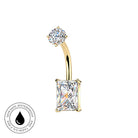Gold curved barbell navel jewelry with a round clear gemstone on one end and a rectangular clear gemstone on the other, shown on a white background with a small circular 'skin-safe waterproof' badge in the lower left.