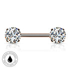 A rose gold barbell piercing jewelry piece with two round-cut clear gemstones, shown on a white background with a reflection below and a small circular 'skin-safe waterproof' badge in the lower-left corner.
