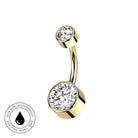 Gold-plated curved navel barbell piercing with two round bezel-set clear cubic zirconia stones, shown on a white background with a circular 'Skin Safe Waterproof' badge in the lower-left corner.