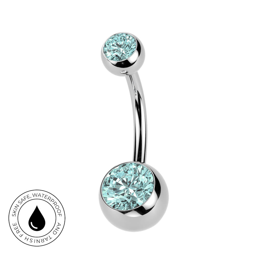 A curved barbell belly button ring with two round bezel-set light blue gemstones on a polished silver-tone metal, shown on a white background with a small circular skin-safe waterproof badge in the lower left.
