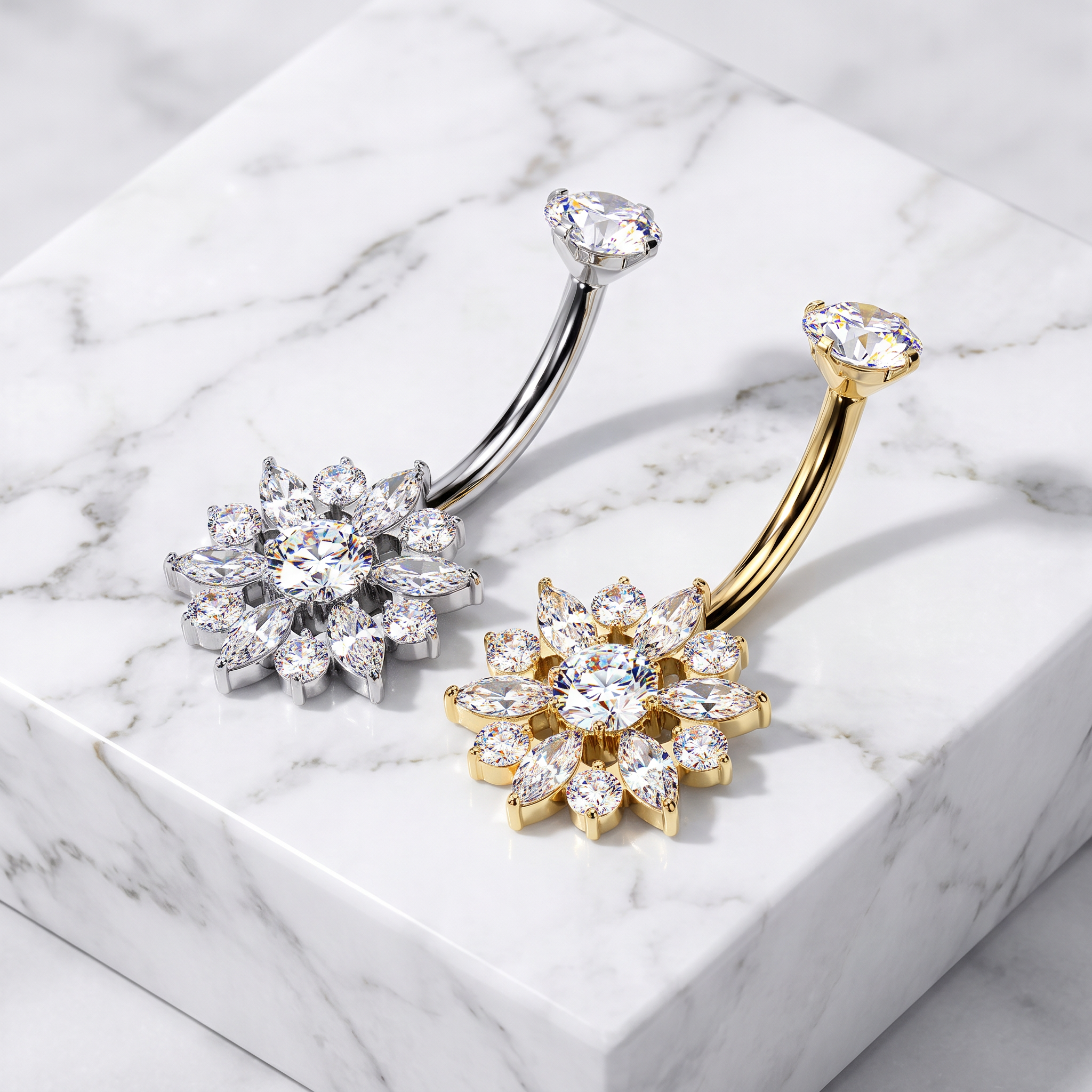 Two flower-shaped belly button rings with clear cubic zirconia stones, one in silver and one in gold, displayed on a white marble block.