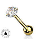 A gold-plated labret piercing barbell with a round-cut clear gemstone in a four-prong setting and a polished ball back, shown on a white background with a small circular 'skin-safe waterproof' badge in the lower left.