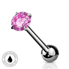 A silver-toned labret piercing barbell with a round faceted pink gemstone on the top and a polished ball back, shown on a white background with a small circular water-resistant badge in the lower left.