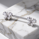 A silver-toned barbell piercing jewelry piece with butterfly-shaped end studs set with clear gemstones, displayed on a white marble block.