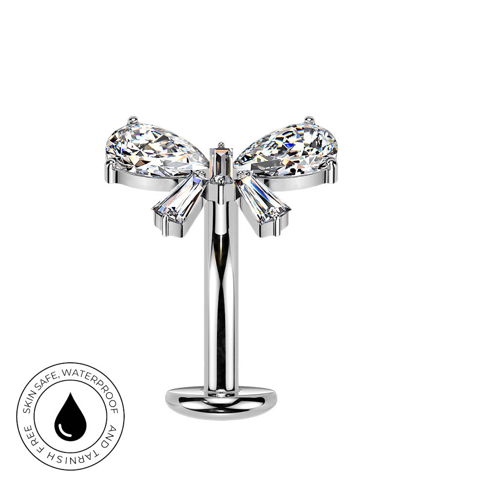 A silver-toned navel piercing stud with a bow design, featuring two marquise-cut clear crystals and two baguette-cut clear crystals, shown on a white background with a circular 'Skin Safe Waterproof' badge in the bottom-left corner.