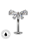 A silver-toned navel piercing stud with a bow design, featuring two marquise-cut clear crystals and two baguette-cut clear crystals, shown on a white background with a circular 'Skin Safe Waterproof' badge in the bottom-left corner.