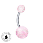 A curved barbell navel piercing with two round, faceted pink glitter top and bottom beads on a silver-tone metal bar, shown on a white background with a circular 'Skin Safe Waterproof' badge in the lower-left corner.