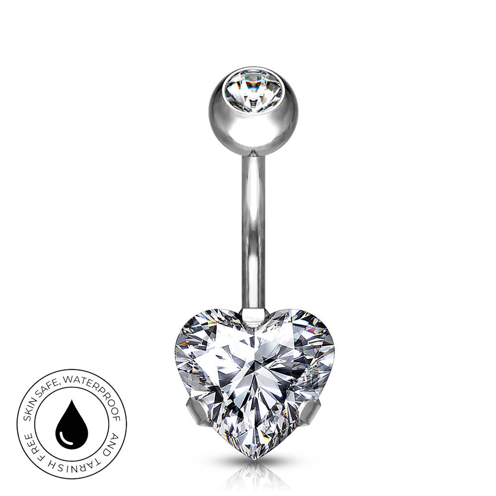 Silver-tone curved barbell belly button ring with a large heart-shaped clear gemstone and a smaller round clear gemstone at the top, shown on a white background with a small circular skin-safe waterproof badge in the lower left.