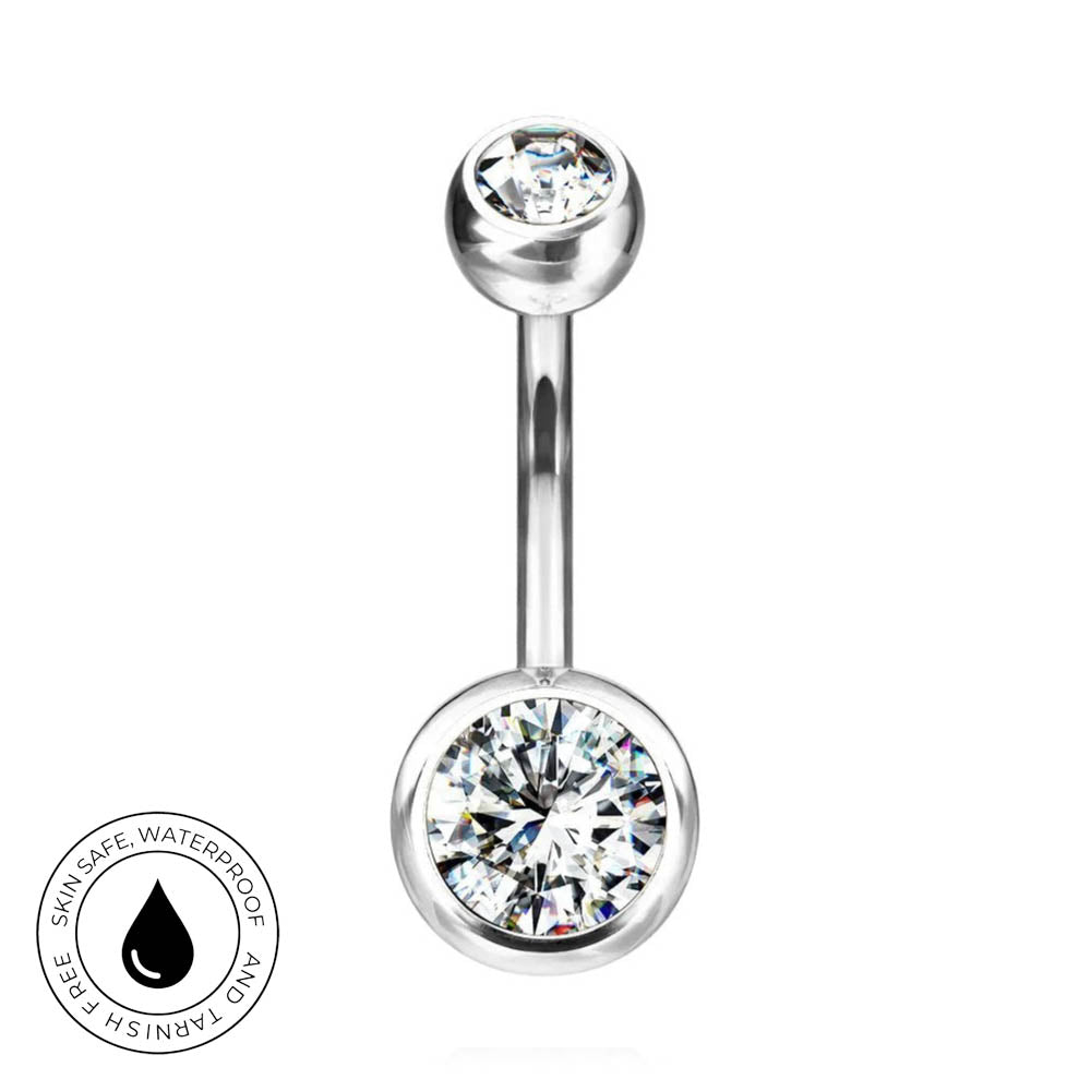 A silver-tone curved barbell navel piercing stud with a large clear round gemstone on the bottom and a smaller clear gemstone on the top, shown on a white background with a circular 'Skin Safe Waterproof' badge in the lower left.