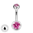 A silver-toned curved barbell belly button ring with a large faceted pink gemstone on the bottom and a smaller pink gemstone on the top, shown on a white background with a circular 'Skin Safe Waterproof' badge in the lower left.