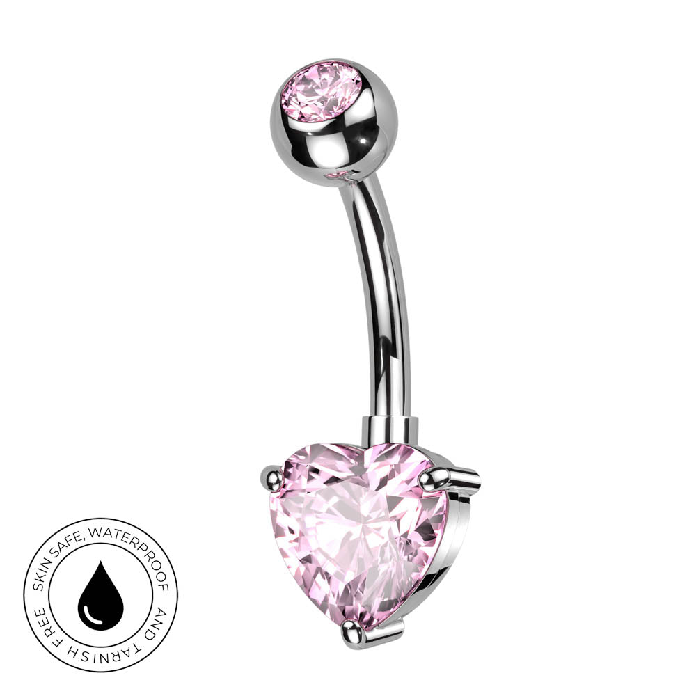 A curved barbell belly button ring with a pink heart-shaped crystal and a smaller pink round crystal at the top, set in silver-toned metal, shown on a white background with a skin-safe waterproof badge.