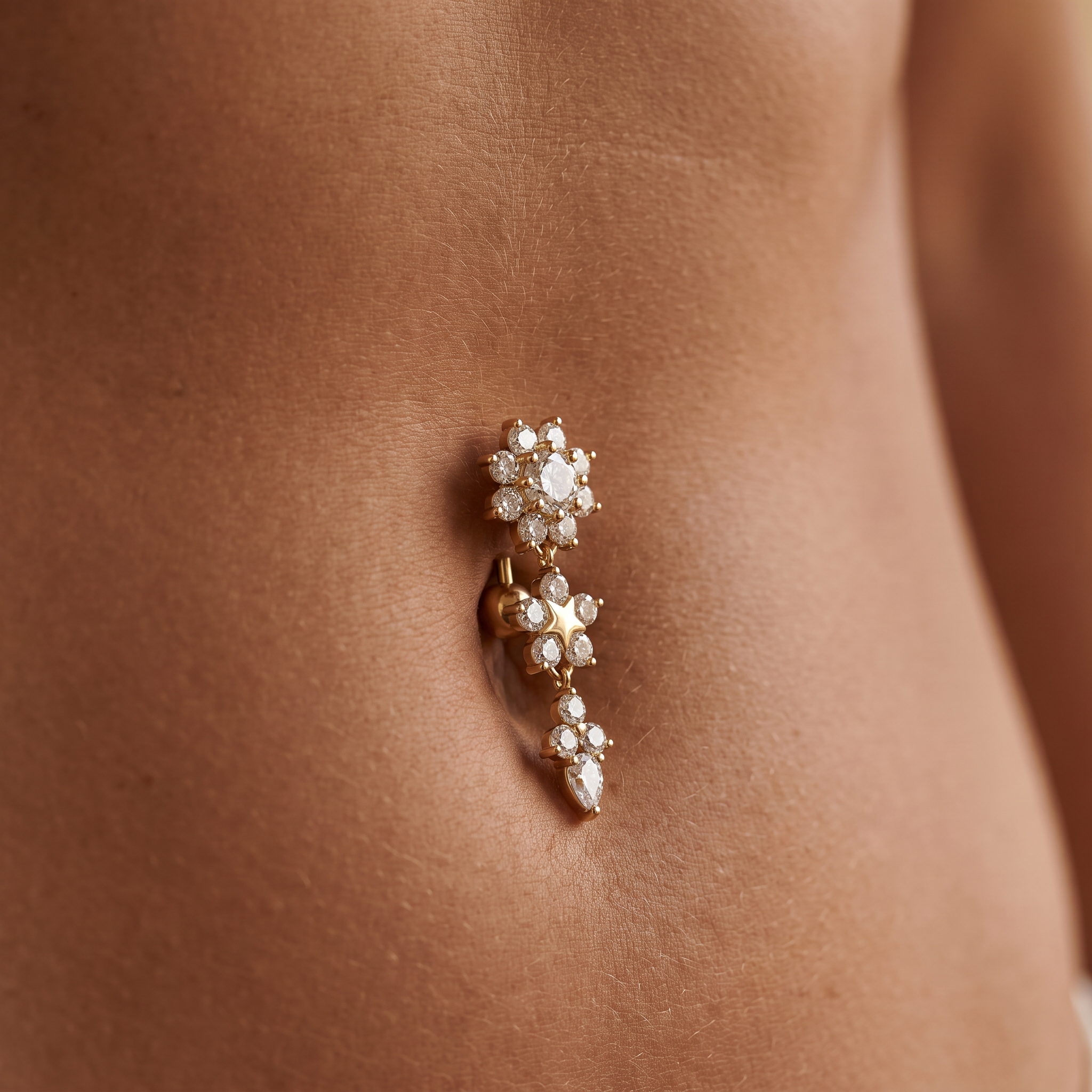 A gold-plated belly button ring with clear rhinestones, shown worn on a person's navel.