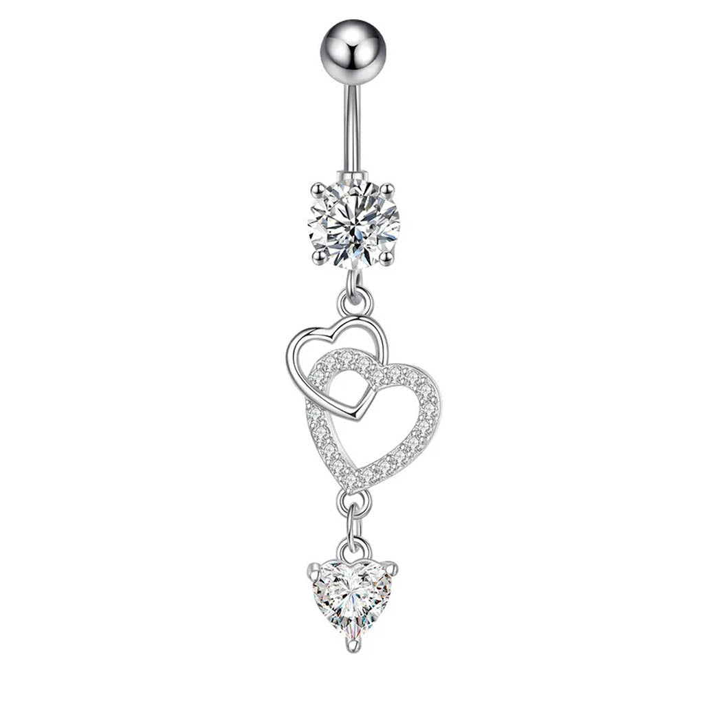 A silver-toned belly button ring featuring a round ball stud, a clear faceted gemstone, and two dangling heart charms adorned with small clear crystals, set against a plain white background.