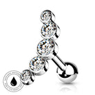 A silver-toned curved barbell belly button piercing with five stacked round bezel-set clear cubic zirconia stones, shown on a white background with a small circular water-resistant badge in the lower left.
