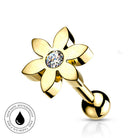 Gold flower-shaped nipple piercing barbell with a clear round-cut gemstone in the center, shown on a white background with a circular skin-safe waterproof badge in the lower-left corner.